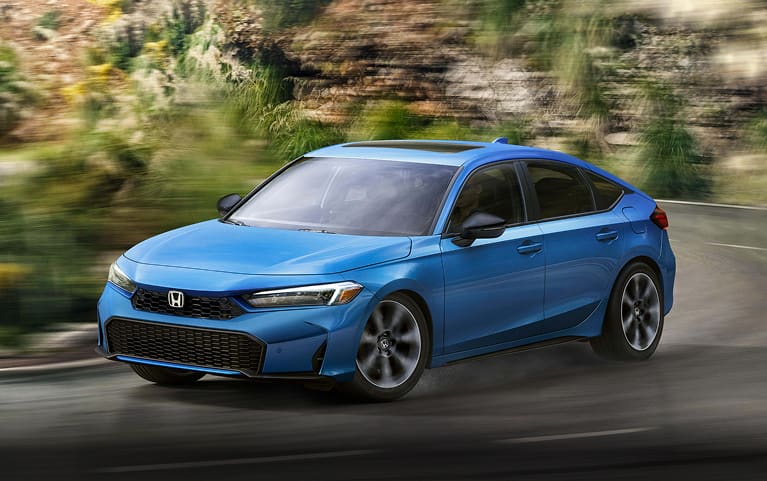 2026 Honda Civic Hatchback Sport Touring Hybrid in Boost Blue Pearl front driving on a winding road (Compact Hatchback).