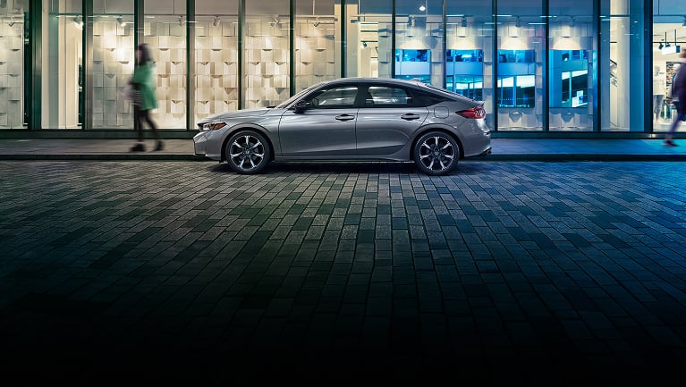 2026 Honda Civic Hatchback Sport Touring Hybrid in Solar Silver Metallic profile parked at night (Compact Hatchback).