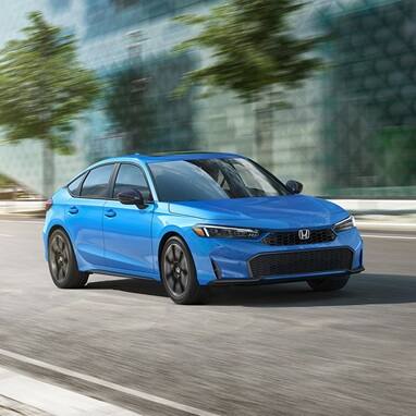 2026 Honda Civic Hatchback Sport Touring Hybrid in Boost Blue Pearl profile driving on a city street (Compact Hatchback).