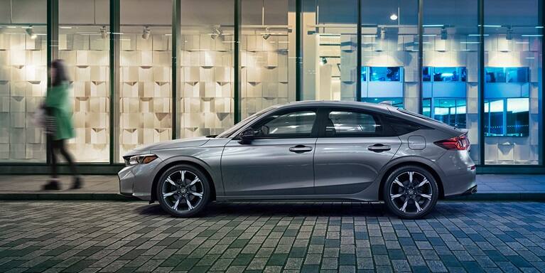 2026 Honda Civic Hatchback Sport Touring Hybrid in Solar Silver Metallic profile parked at night (Compact Hatchback).