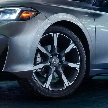 2026 Honda Civic Hatchback Sport Touring Hybrid in Solar Silver Metallic profile in a modern studio setting (Compact Hatchback).