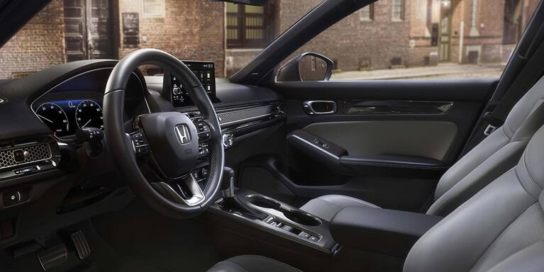 2026 Honda Civic Hatchback Touring Hybrid front cabin with leather-trimmed seats and dashboard (Compact Hatchback).