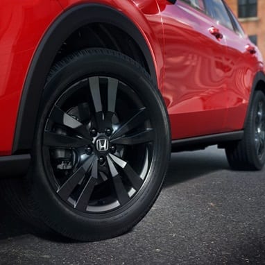 2027 Honda HR-V Sport in Milano Red close up of 18-inch gloss-black alloy wheels (Subcompact Crossover SUV).