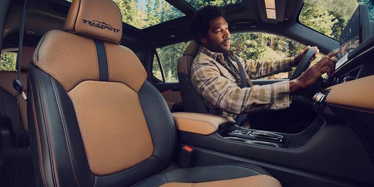 2027 Honda Passport TrailSport Elite leather seats and dashboard with driver using the touchscreen (Mid-Size SUV).